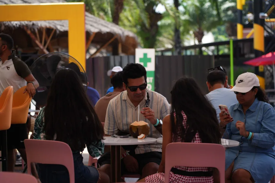 Team members relaxing at café tables, one drinking from a fresh coconut