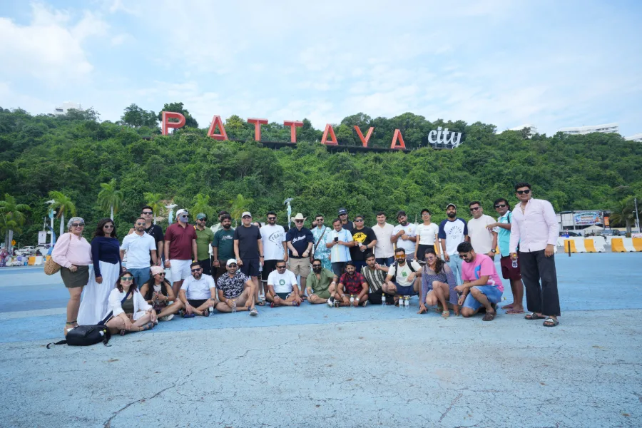 The Adiona team posing as a large group below the red Pattaya City sign on the hillside