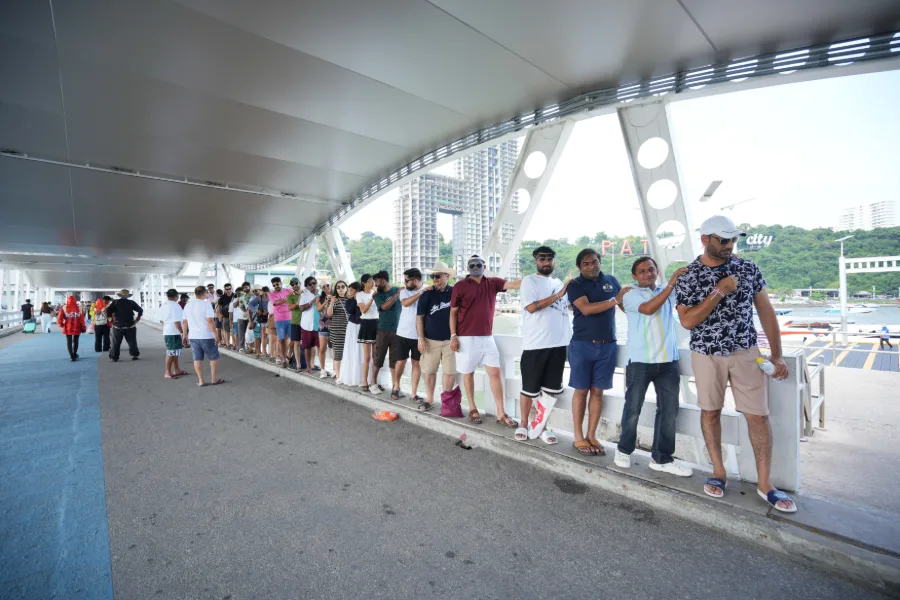 The team standing in a long line on a covered pier, hands on each other’s shoulders