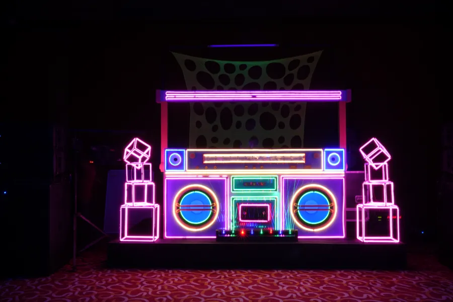 A glowing neon boombox set piece at a theme party