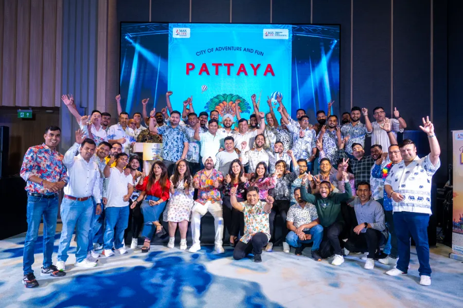 An incentive group cheering on stage under a Pattaya banner